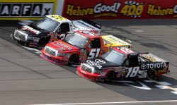 On lap 93, No. 51 Aric Almirola, No. 30 Todd Bodine and No. 18 Kyle Busch got three-wide across the start-finish line in the NASCAR Camping World Truck Series VFW 200 Saturday at Michigan International Speedway in Brooklyn, Mich. Credit: Jerry Markland/Getty Images for NASCAR